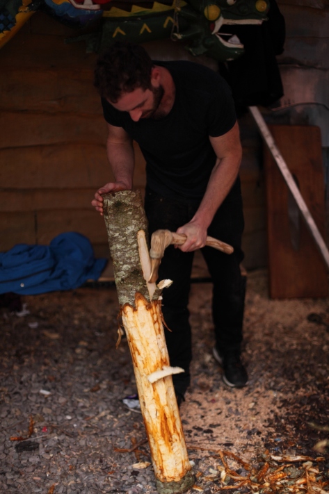 Figure 5: Me using the axe to slide off the bark. NB: the red and orange staining in contrast to the fresher white wood. Photo: Brian Mac Domhnaill. 